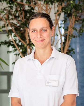 Vier medizinische Fachkräfte in weißer Kleidung stehen in einem modernen Krankenhausumfeld. Sie lächeln und posieren gemeinsam.